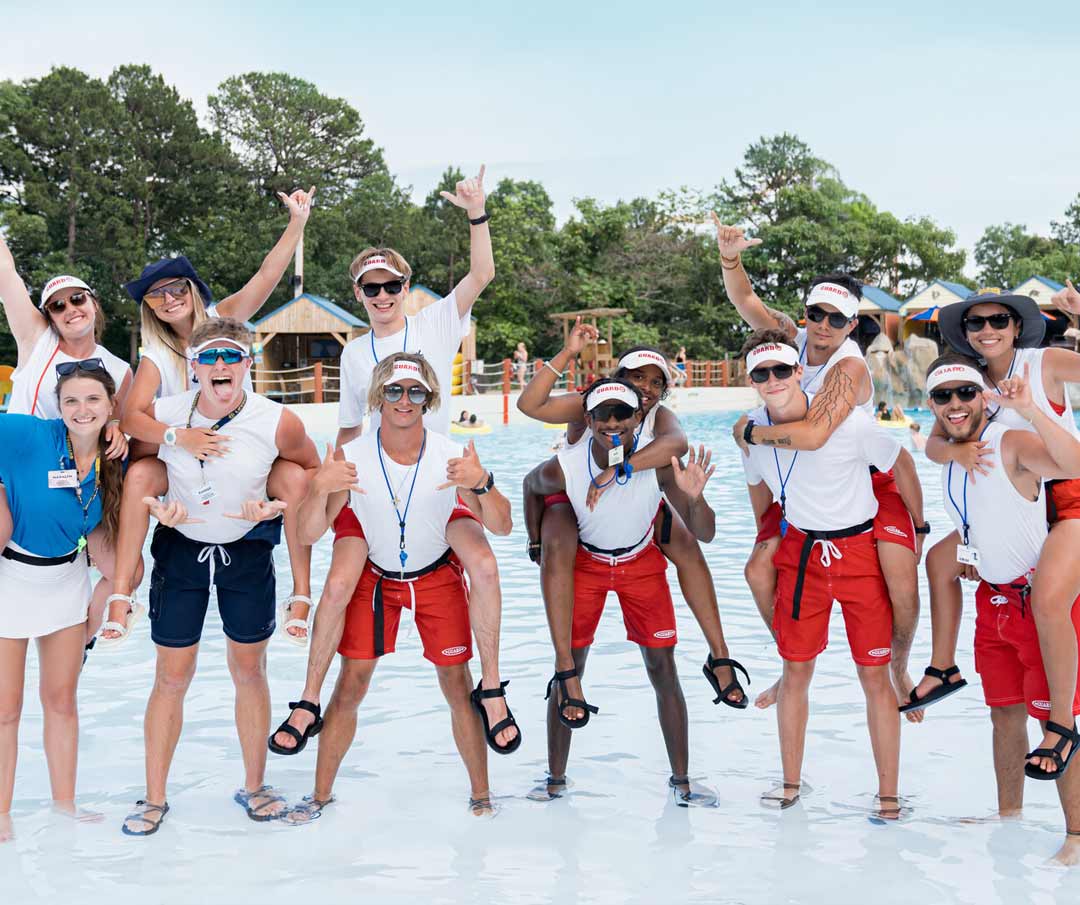 group-of-lifeguards Group of lifeguards laughing and posing for a group photo by the wave pool